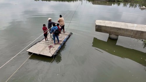 A falta de puente, cruzan en balsa el Río San Juan